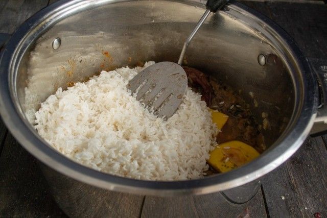 Додаємо рис, головку часнику і гарячу воду